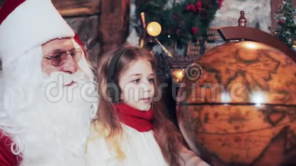 圣诞老人和一个美丽的女孩正在观看地球上旋转的国家视频的预览图