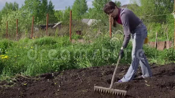 女农民用耙子把地铲平视频的预览图