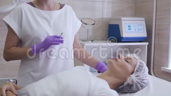 戴紫色手套的医生在女人嘴唇上注射视频的预览图