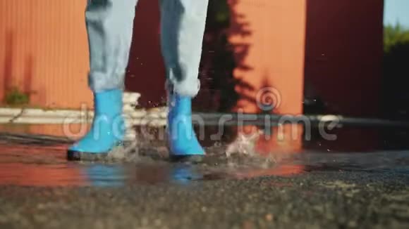 穿着胶靴的女性腿在地上的水坑里跳享受秋天视频的预览图