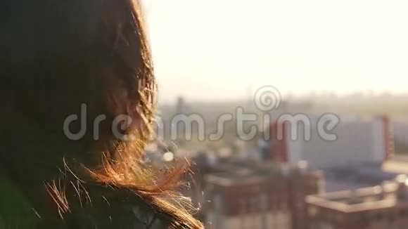 特写一个女孩站在屋顶上的肖像欣赏城市的景色慢动作视频的预览图