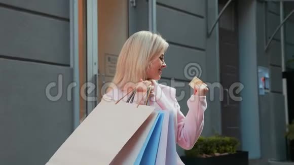 带着纸袋和信用卡的女士在买衣服后愉快地旋转着视频的预览图