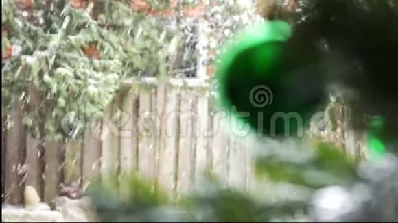 模糊的绿色圣诞树玩具挂在窗户背景上的圣诞树上外面可见下雪视频的预览图
