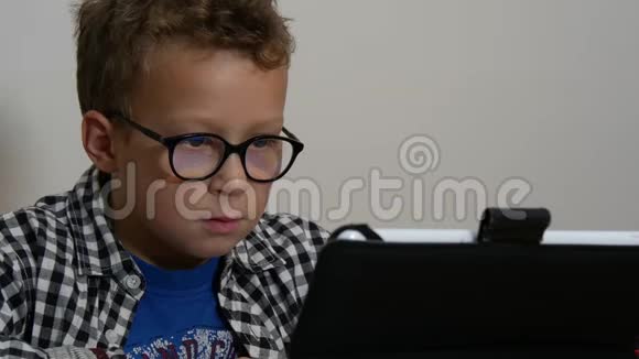 带平板电脑的小男孩坐在家里的桌子上视频的预览图