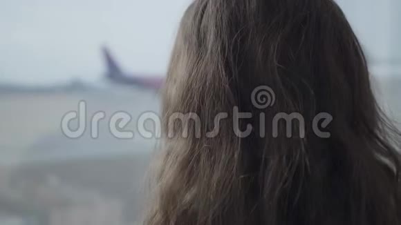 后景特写白种人女孩卷发看飞机起飞通过大机场窗口儿童视频的预览图