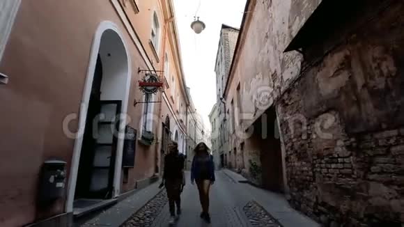 沿着欧洲城市的古老街道行走两个年轻的女人走在维尔纽斯老城狭窄的街道上二视频的预览图