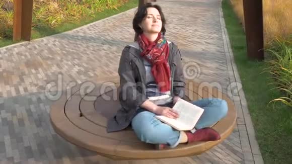 白种人女人闭上眼睛骑在旋转木马上书躺在她的膝盖上视频的预览图