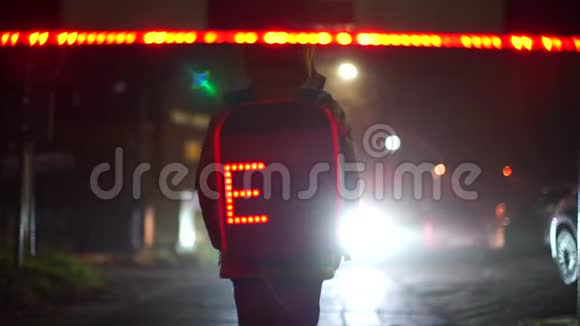 一个带着发光背包的小学生晚上站在学校的人行横道上视频的预览图