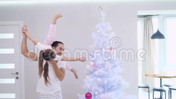 活泼的父亲和他运动的女儿在父亲肩膀上的分裂位置正在一起装饰杉树视频的预览图