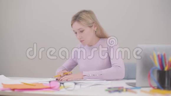 一个年轻的金发白种人女人的波特拉伊坐在办公室里画蓝图她的男同事视频的预览图