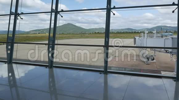 现代化的机场透过窗户看到美丽的跑道和客运码头山脉背景视频的预览图