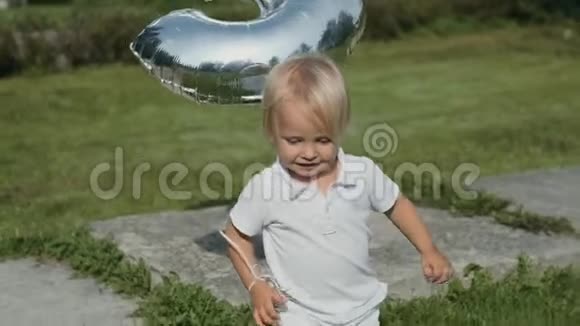 天气晴朗穿着白色衣服的漂亮小男孩在草地上奔跑视频的预览图