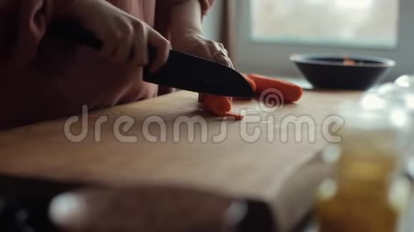 一位年轻女子用一把大刀切胡萝卜在厨房里做饭视频的预览图