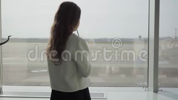 后景白种人女孩留着长长的卷发机场的大窗户喝着果汁等待的儿童视频的预览图