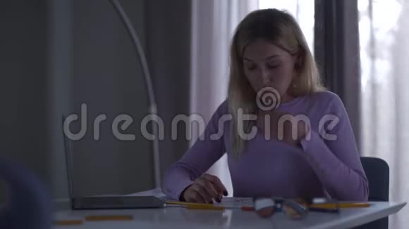 年轻疲惫的白种人女孩揉着眼睛看着笔记本电脑的屏幕从事新工作的女性专家视频的预览图