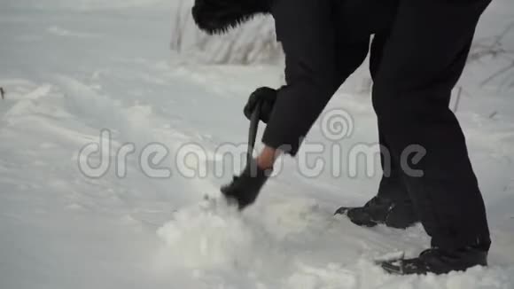 一个人从森林道路上移除雪来驾驶汽车用一把折叠的小铲子把雪摇回来视频的预览图