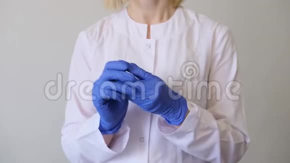 一位身穿白色制服的女医生脱下蓝色手套卫生治疗医药概念视频的预览图