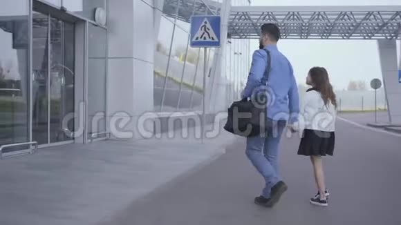 成年白种人穿着休闲蓝色衣服小女孩留着长长的卷发进入机场门父亲和视频的预览图