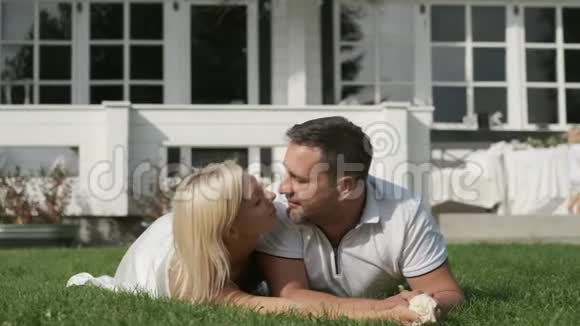 爱的一对吻躺在房子附近的草地上视频的预览图