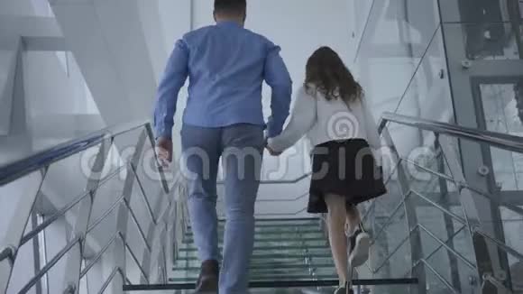 年轻父亲带着女儿走上机场的现代楼梯的后景穿休闲服装的男人和女孩视频的预览图