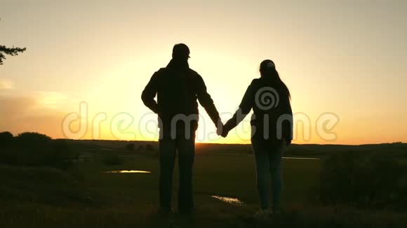 旅行者男女两手相握日落时欣赏风景情侣旅行者带背包旅行视频的预览图