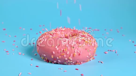 彩色配料在蓝色背景上美味的粉红色甜甜圈的顶部甜食和糖的营养理念视频的预览图