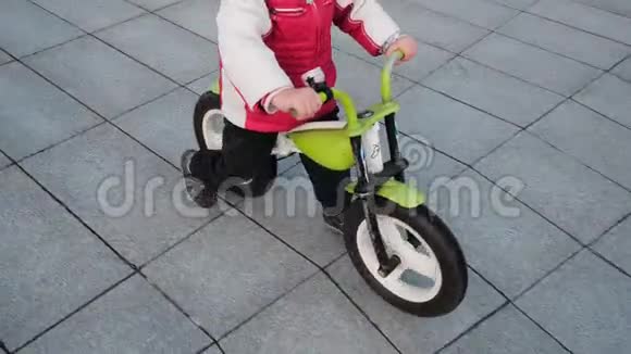 微笑的小男孩正骑着绿色自行车在一个城市公园特写城市公园里戴着头盔的小比克人视频的预览图