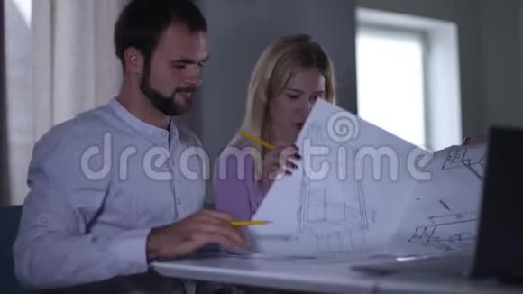 年轻迷人的白种人女孩翻阅蓝图向她的男同事解释整个项目的想法视频的预览图