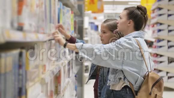 快乐的女孩子和她迷人的母亲在超市里一起选择平板游戏视频的预览图