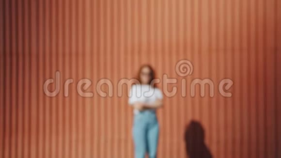 戴墨镜的红发女孩站在户外靠近墙壁的变焦肖像视频的预览图