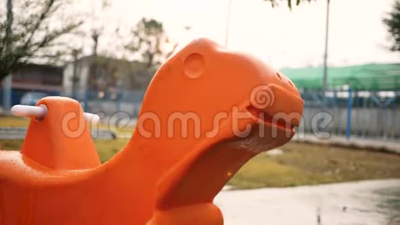 橙色塑料摇摆马在操场户外视频的预览图