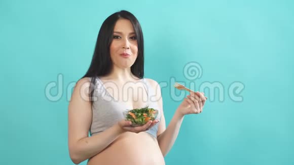 大肚子孕妇吃蓝墙隔离的蔬菜沙拉视频的预览图