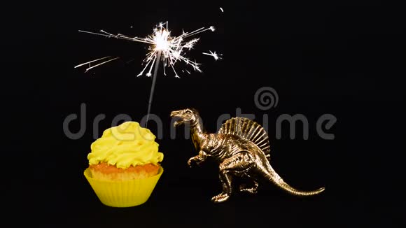 金色恐龙和闪闪发光的亮黄色纸杯蛋糕隔离在黑色背景生日快乐高清视频视频的预览图