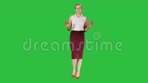 可爱的女商人看着摄像机在绿色屏幕上走着说话彩色键视频的预览图
