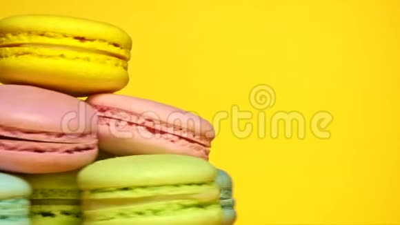 五颜六色的美味杏仁饼在黄色背景上旋转视频的预览图