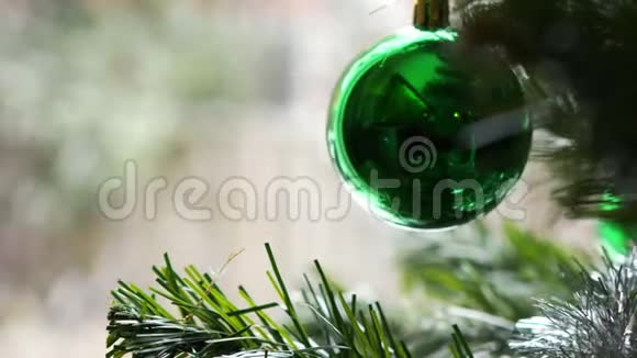 绿色圣诞树玩具挂在窗户背景上的圣诞树上外面可见模糊的积雪视频的预览图