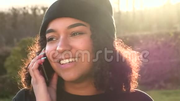 美国黑人少女少女在傍晚阳光下用手机背光聊天视频的预览图