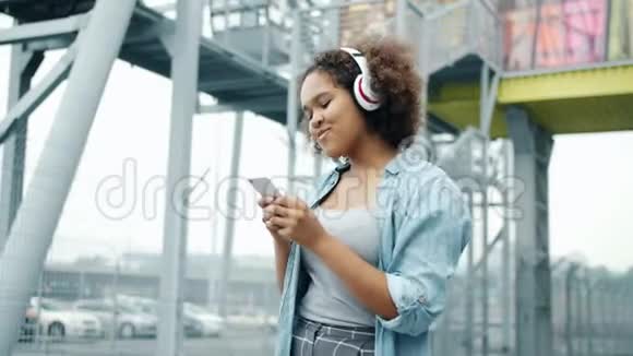 使用智能手机在户外欣赏音乐的非裔美国青少年慢动作视频的预览图