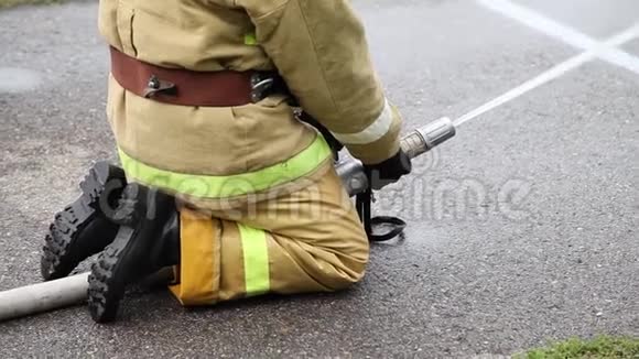 一名消防队员坐着用消防水带灭火视频的预览图
