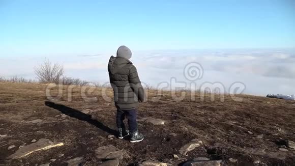小男孩站在山顶望着远处的云彩视频的预览图
