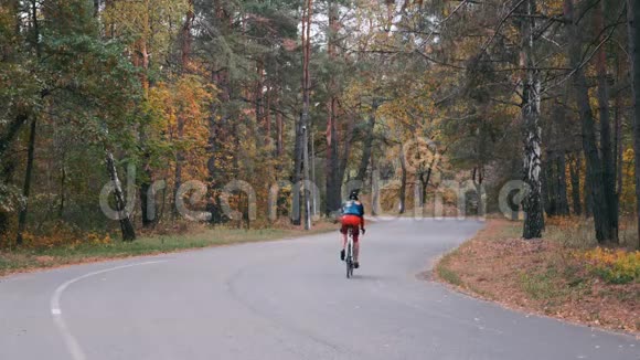 两名有魅力的男三项运动员正在秋季公园进行公路自行车训练穿着运动服和头盔骑自行车的年轻骑自行车者视频的预览图