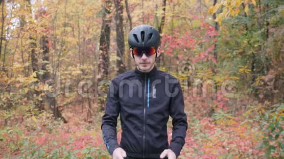 职业男性自行车运动员戴着黑色头盔和眼镜在骑自行车训练前戴上自行车手套骑自行车的人准备视频的预览图