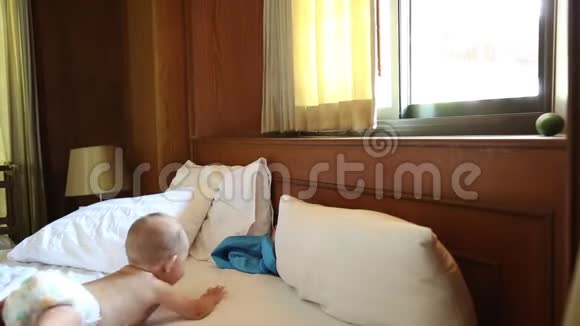 尿布上的婴儿滑稽地爬在床上向窗户爬去视频的预览图