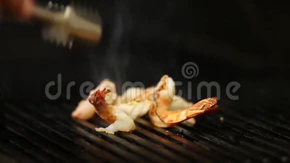 在烤架上库克的特写镜头把烟熏的虾翻过来视频的预览图