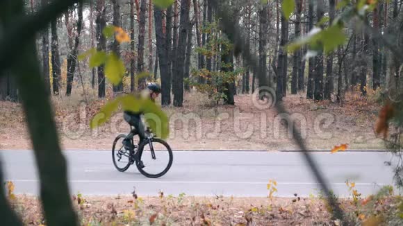自行车运动员黑色头盔和运动太阳镜训练在道路自行车在秋季森林年轻人骑自行车出去视频的预览图