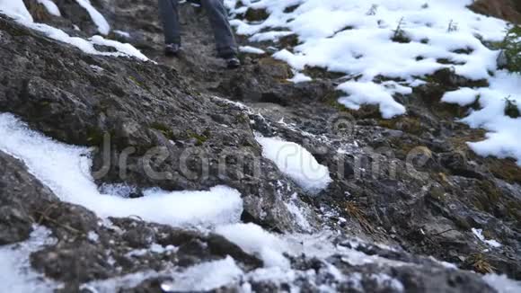年轻徒步旅行者的脚在旅行中沿着岩石斜坡行走男游客的腿下了雪山健康视频的预览图