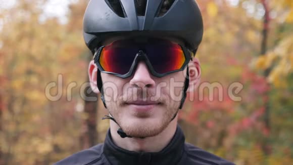 迷人的白种人专业自行车寻找相机和摘下运动眼镜后锻炼自行车在秋季公园Cyc视频的预览图