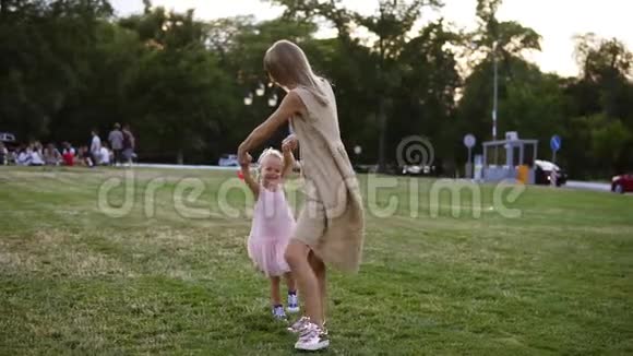可爱的白种人母亲穿着米色连衣裙她的小女儿在公园里玩得很开心妈妈在旋转视频的预览图