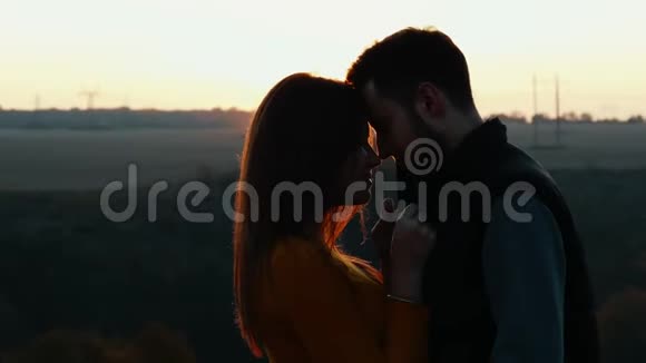 在夕阳下温柔地亲吻可爱的年轻夫妇视频的预览图