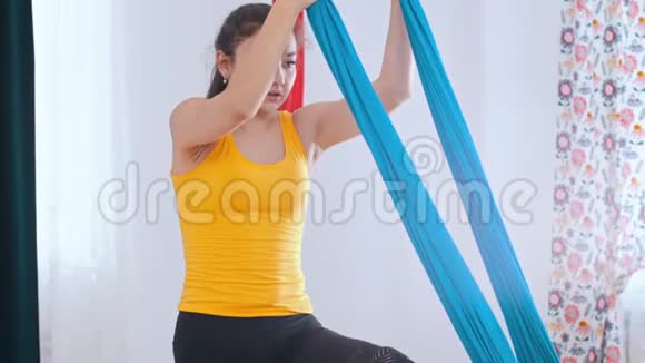 空中瑜伽一个女人爬上吊床做瑜伽视频的预览图